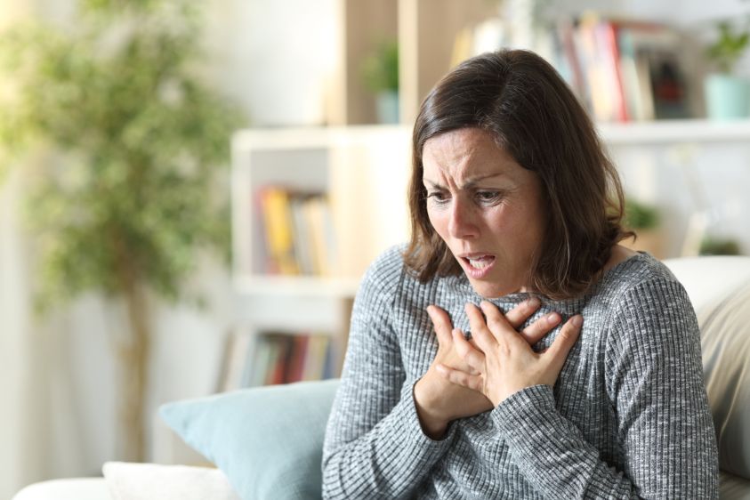 Middle age woman wheezing touching chest at home