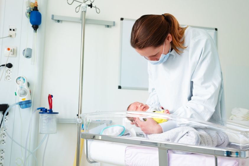 Nurse in ICU examining premature born infant